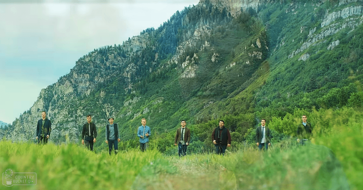 Young adult males standing together in a rural mountainous landscape, wearing casual and semi-formal attire.