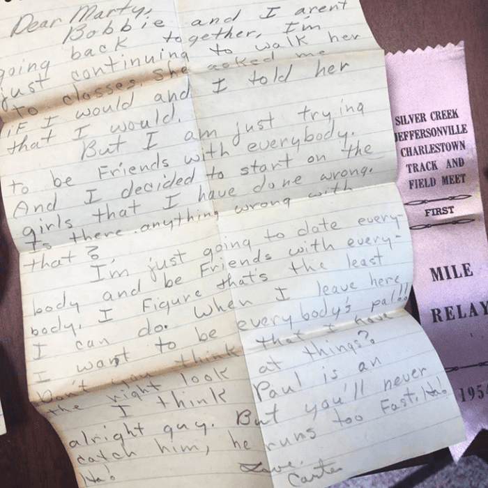 A handwritten letter from the mid-20th century with a purple ribbon on a brown background, natural daylight setting
