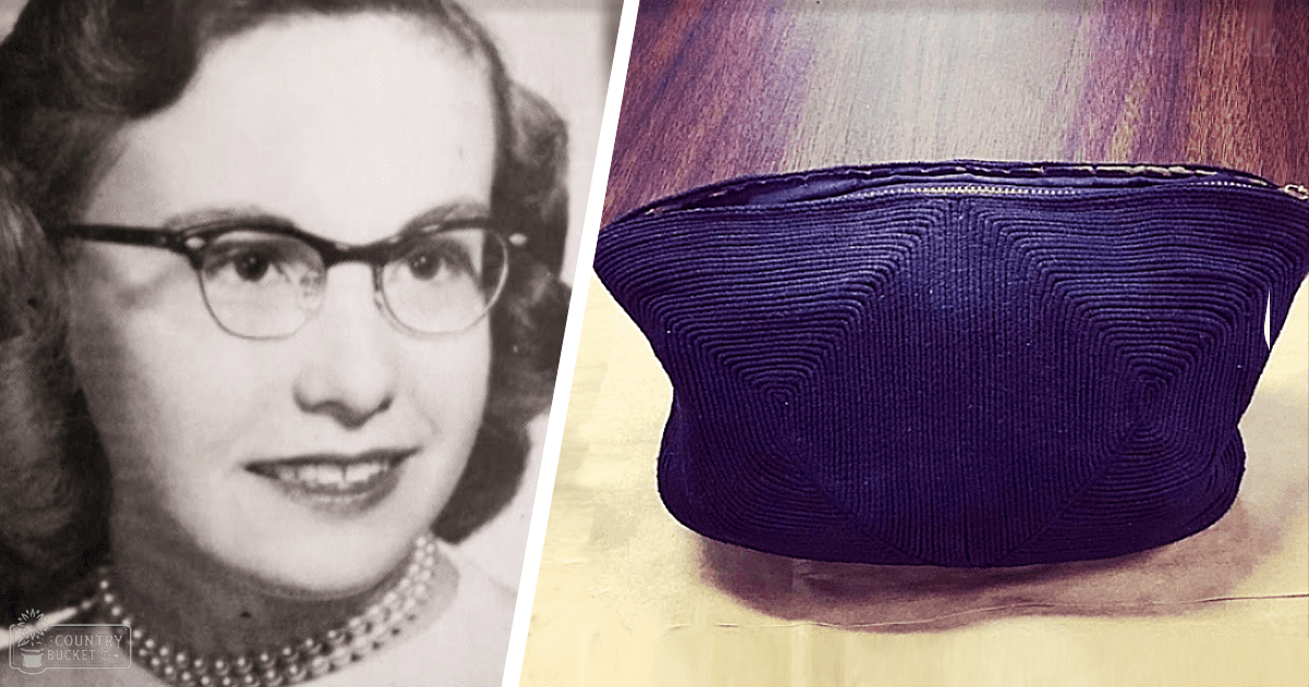 Middle-aged adult female wearing pearl necklace, glasses with thick frames, light-colored garment; purple handbag with geometric pattern in foreground indoors.