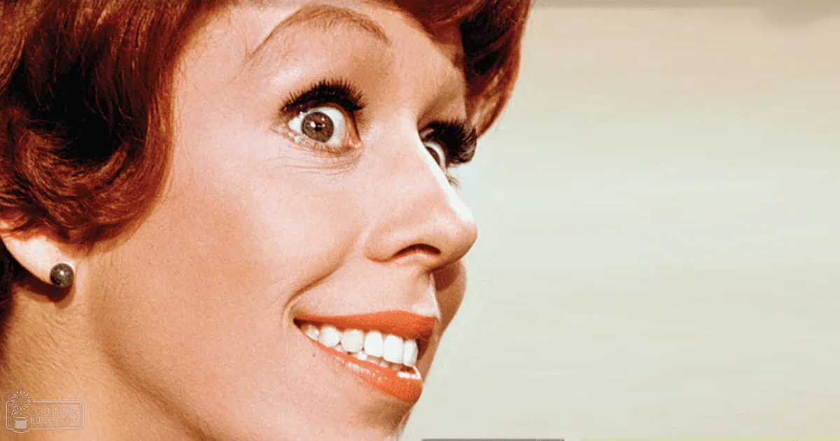 An adult female wearing small dark earrings in an indoor setting with neutral lighting and a light-colored background.