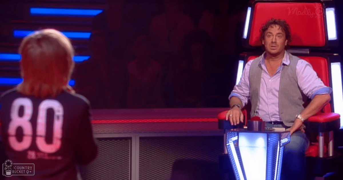 A young adult male and a child in an indoor talent show setting with red and blue lighting.