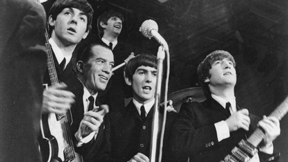 A musical performance with The Beatles with a guest performer on stage in the late 1960s.