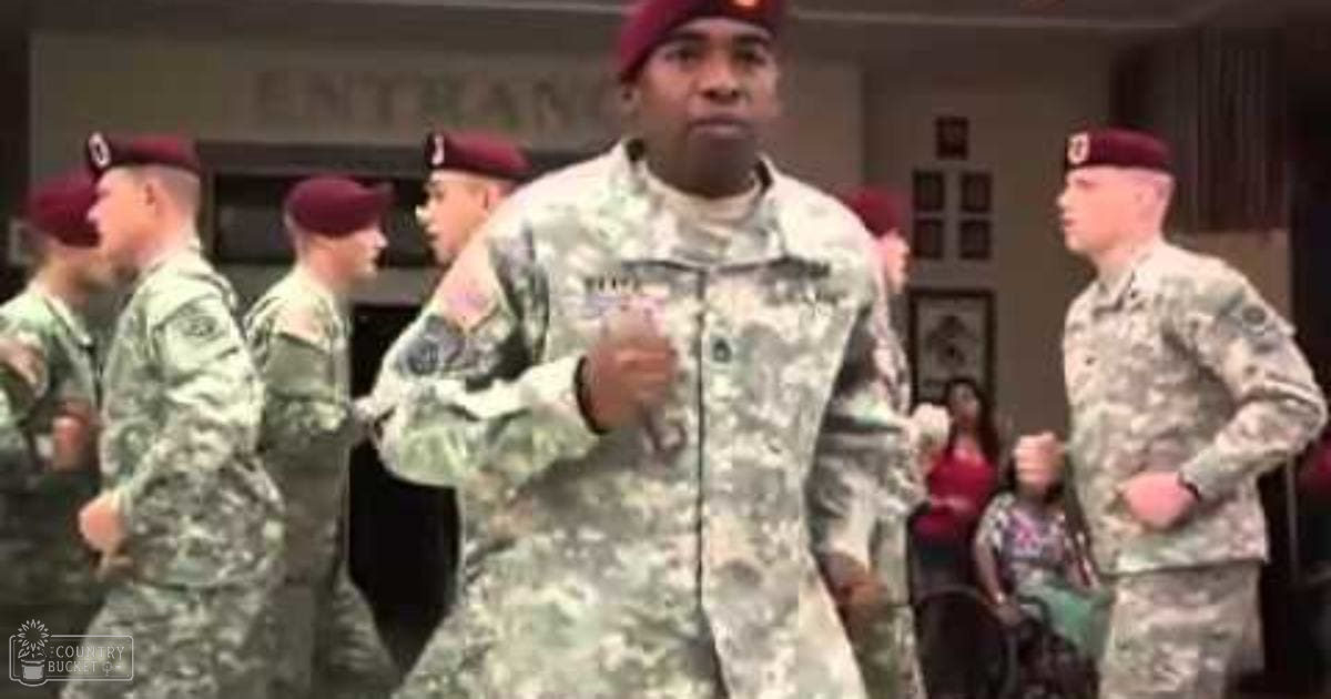 A group of men in camouflage military uniforms, including a man wearing a beret with patches on his sleeves, standing indoors at what appears to be a veterans' facility.