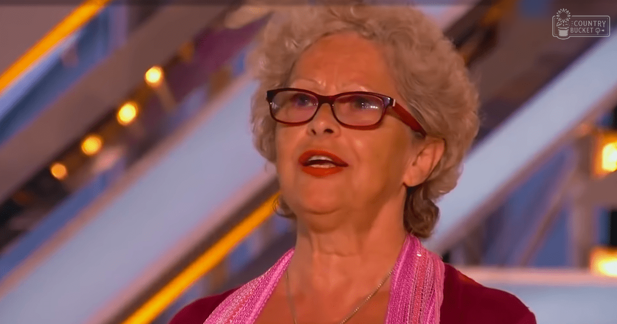 A formally dressed older adult female wearing a maroon sequined blouse with rectangular-framed glasses and a necklace, set against geometric shapes and artificial lighting in an indoor studio environment.