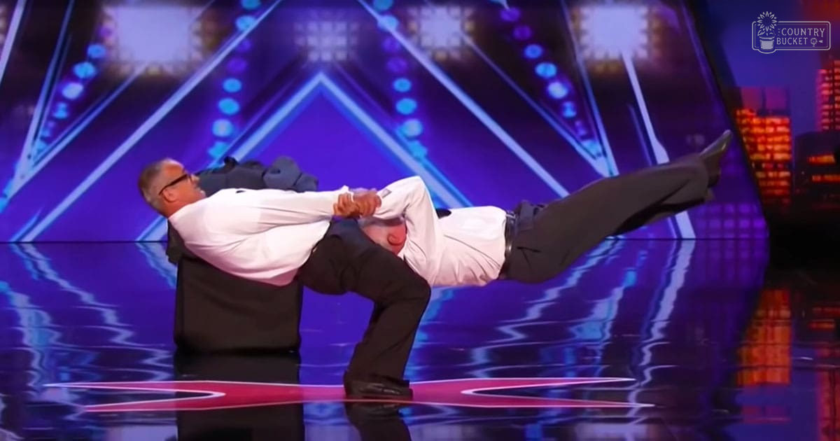 A middle-aged male martial artist performs a move on a brightly lit stage, with dynamic blue and purple lighting, during what appears to be a talent show.