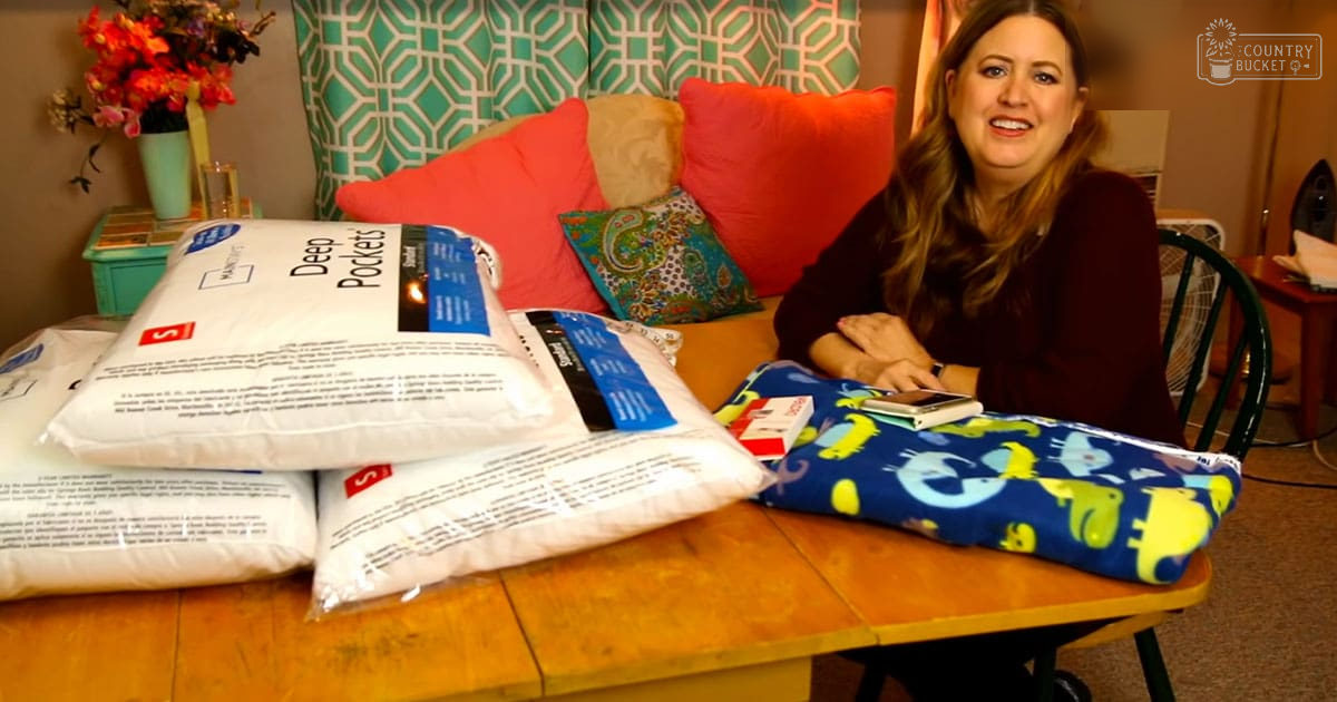 Adult female wearing a dark red long-sleeved top in an indoor setting with wooden furniture, teal curtains, and various pillows.