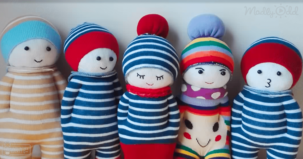 Handmade dolls with striped onesies and red knit hats in an indoor home setting