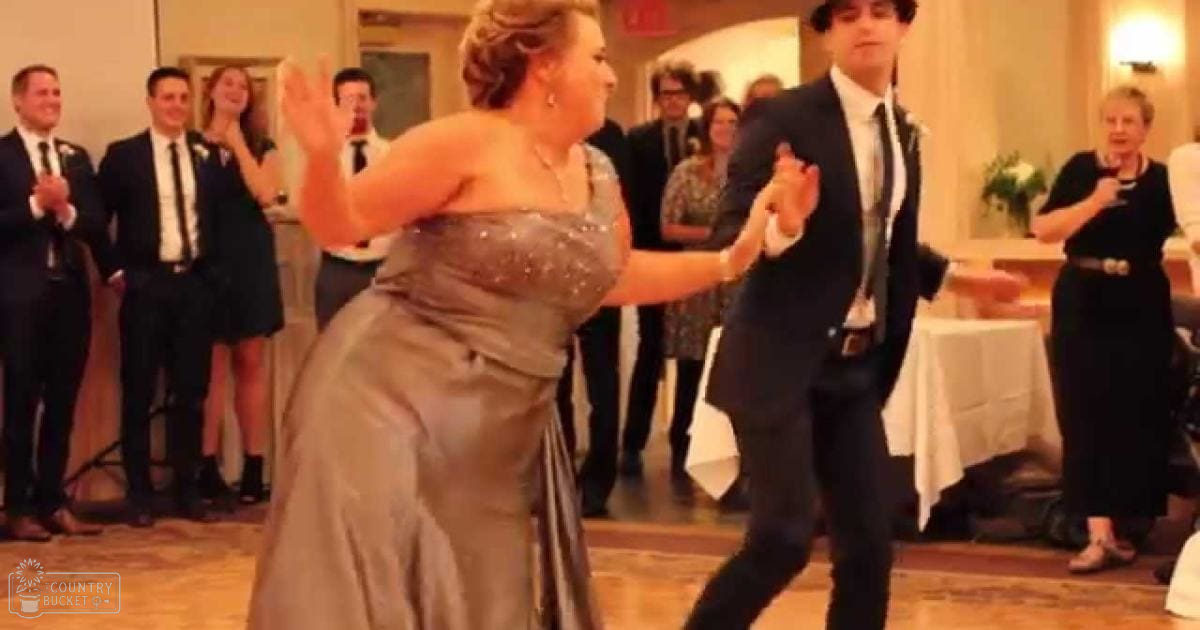 A couple in formal attire dancing at an indoor event, likely a wedding reception.