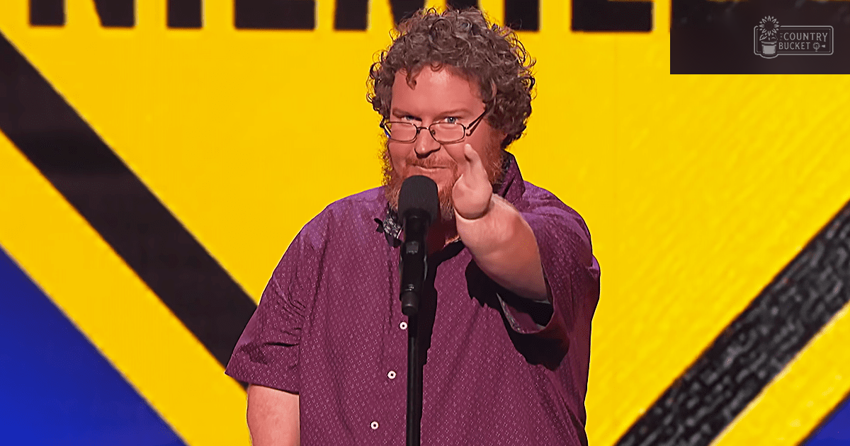 A middle-aged adult male wearing a relaxed fit short-sleeved button-up shirt with small dots pattern in an indoor setting with bold yellow with black diagonal stripes on the backdrop.