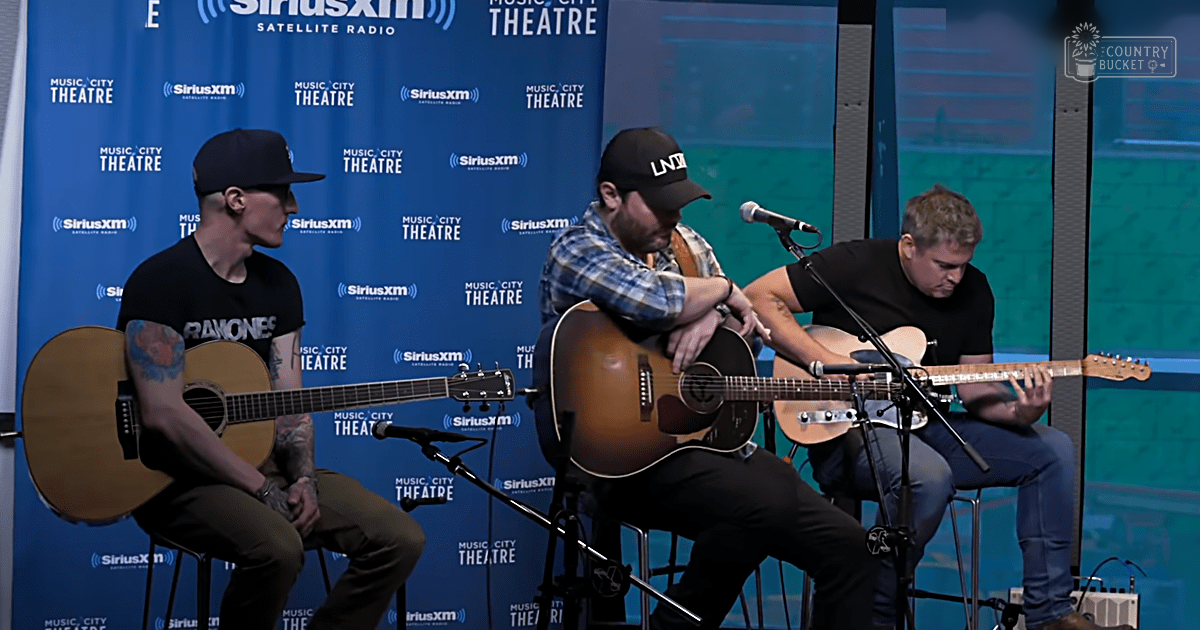 Musical performance at SiriusXM Music City Theatre; adult males playing acoustic guitars in a bright, indoor setting with blue backdrop and logos.