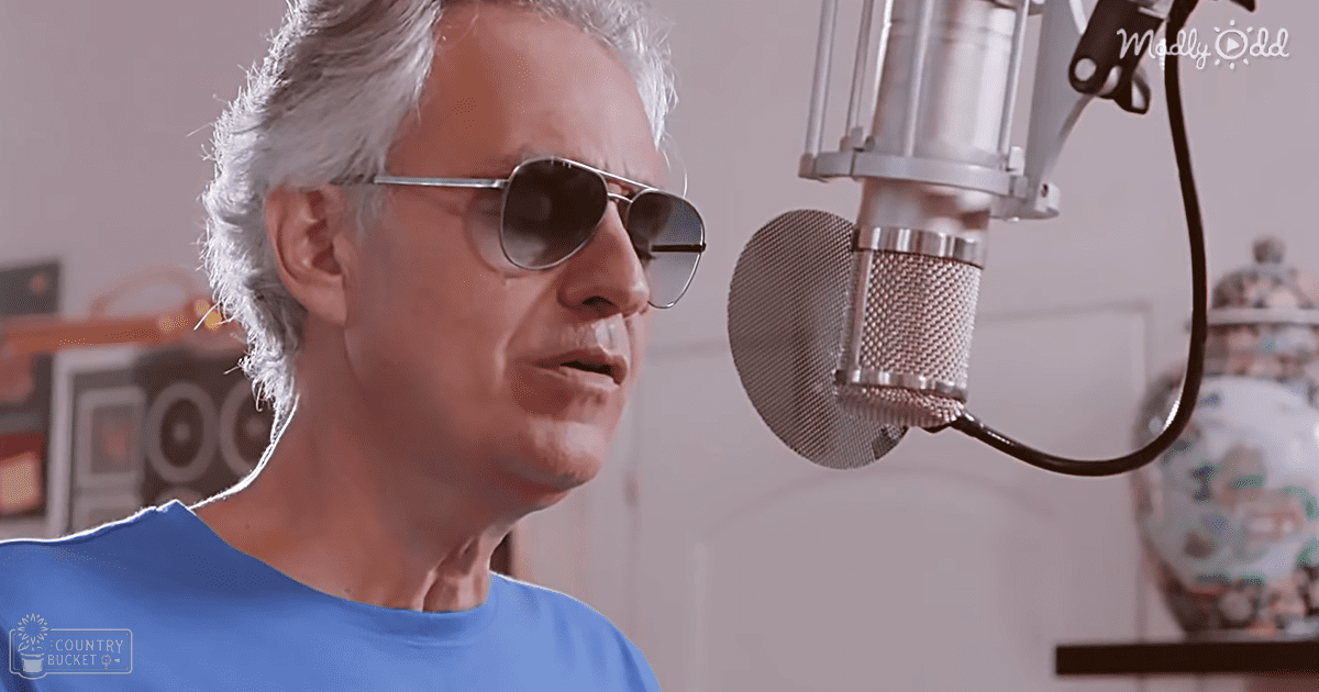 Middle-aged man with aviator sunglasses, blue t-shirt in professional recording studio with microphone and decorative items