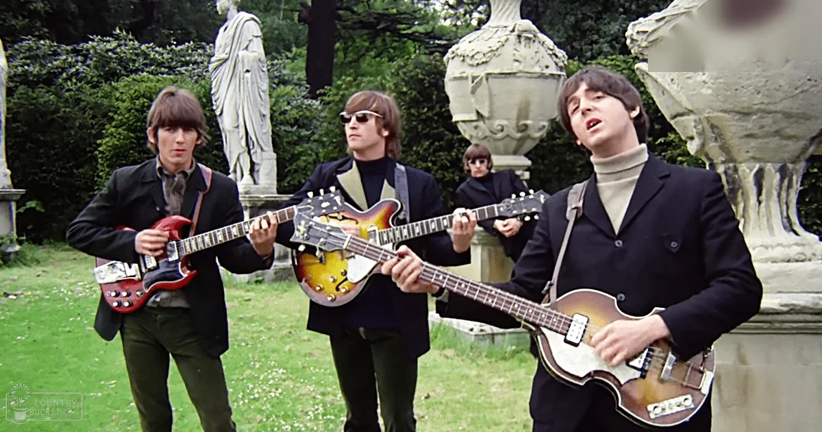 Four young adult males playing electric guitars outdoors, with statues and greenery in a garden setting during late afternoon.