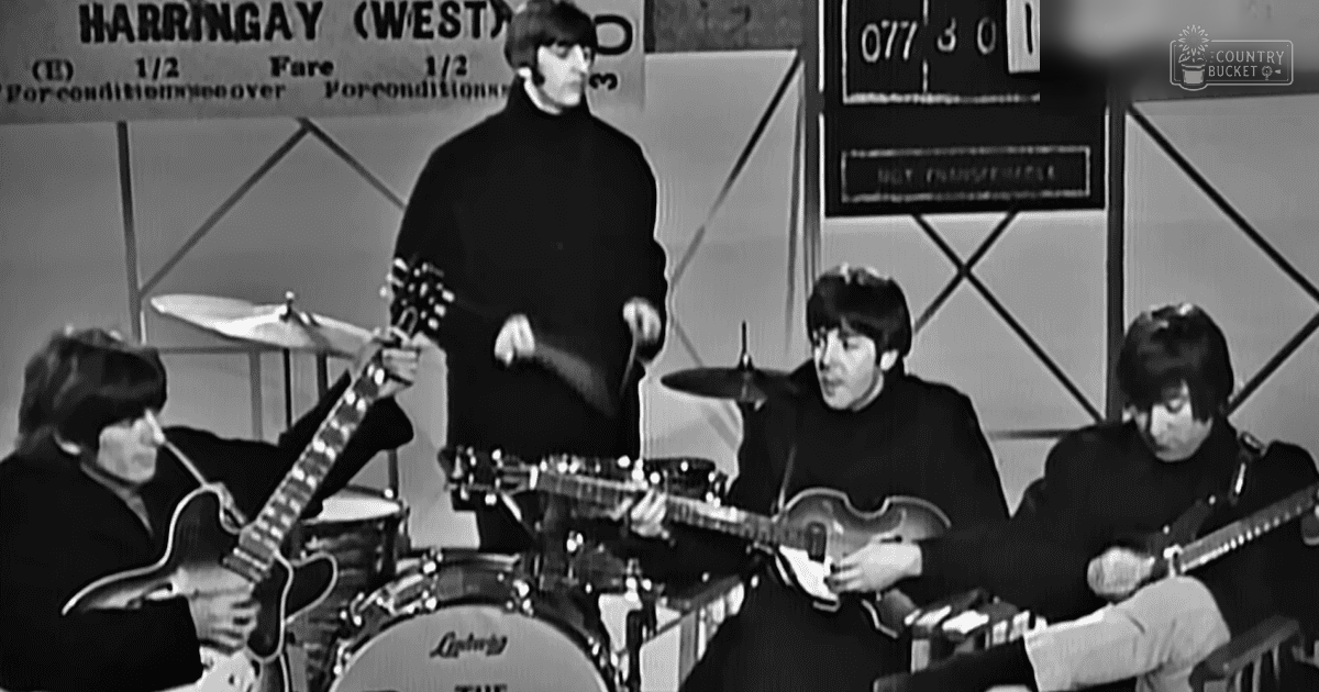 A musical performance with young adult males in dark clothing on a stage at Harringay (West), England, under artificial lighting.