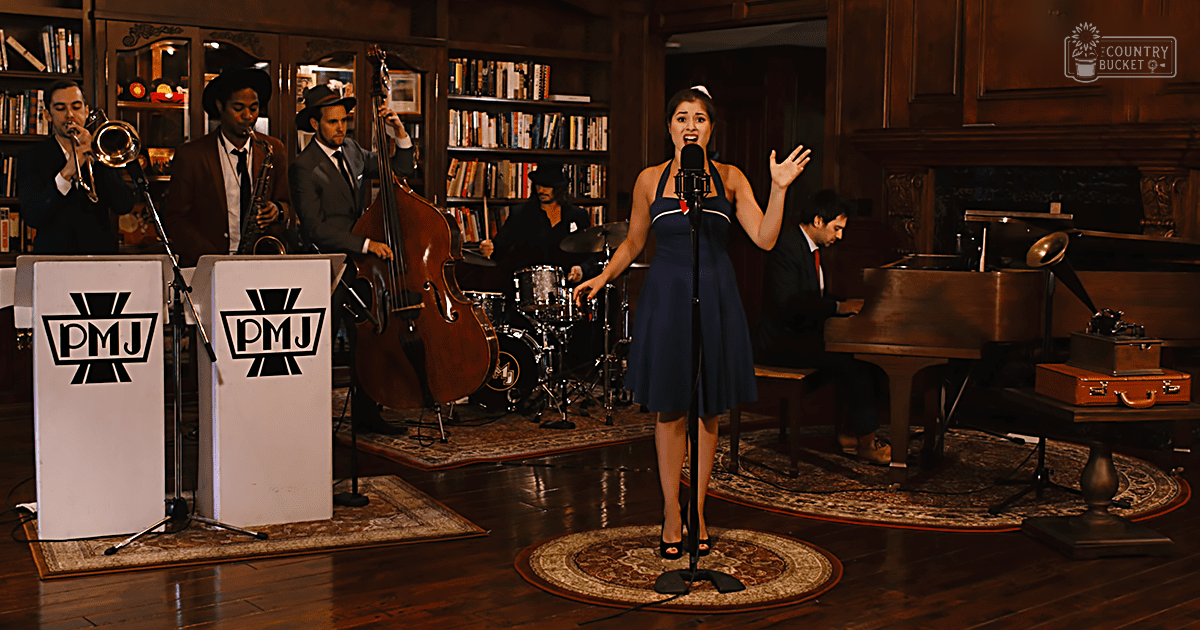 A woman singing in front of a jazz band, with vintage decor elements like bookshelves filled with books and a phonograph on the right side. The setting appears to be an indoor venue with wooden floors and a large fireplace.