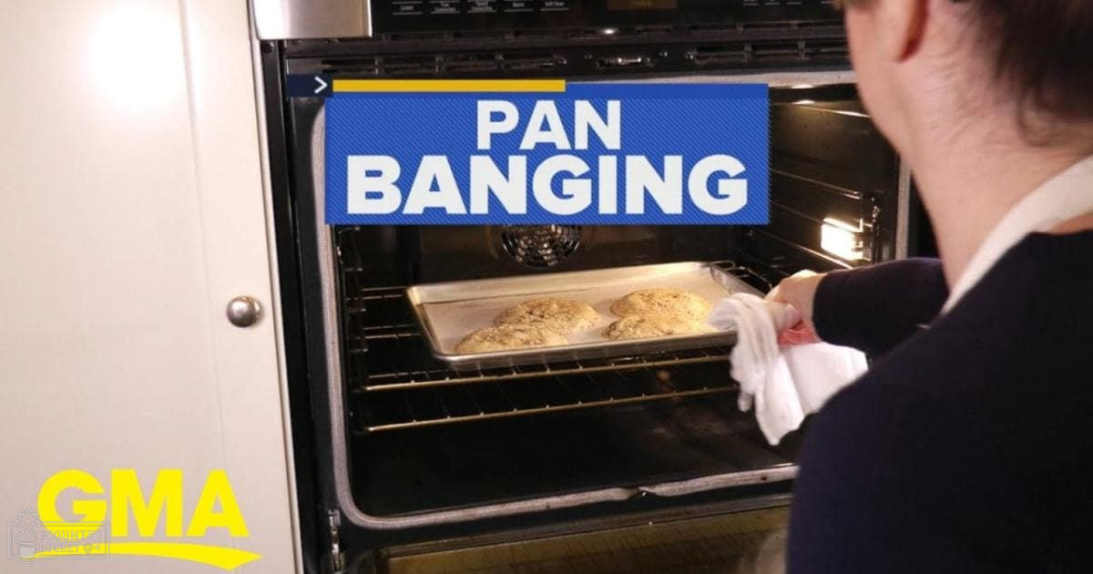 An adult female in a modern casual dark-colored long-sleeve top with a white collar, baking cookies in an oven indoors.