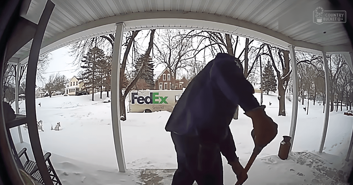 A middle-aged man shoveling snow with a small dog nearby, set against an overcast winter day at a residential porch.