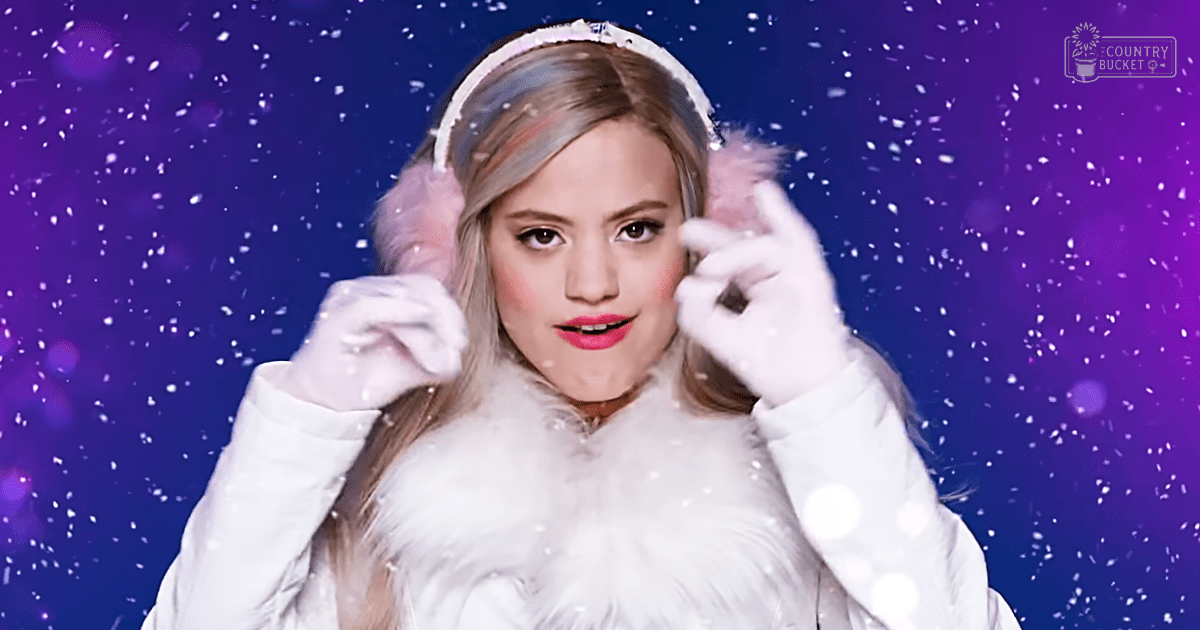 Young adult female wearing a white fur coat with high collar, fluffy trim, and polka-dotted white gloves against a purple winter-themed backdrop.