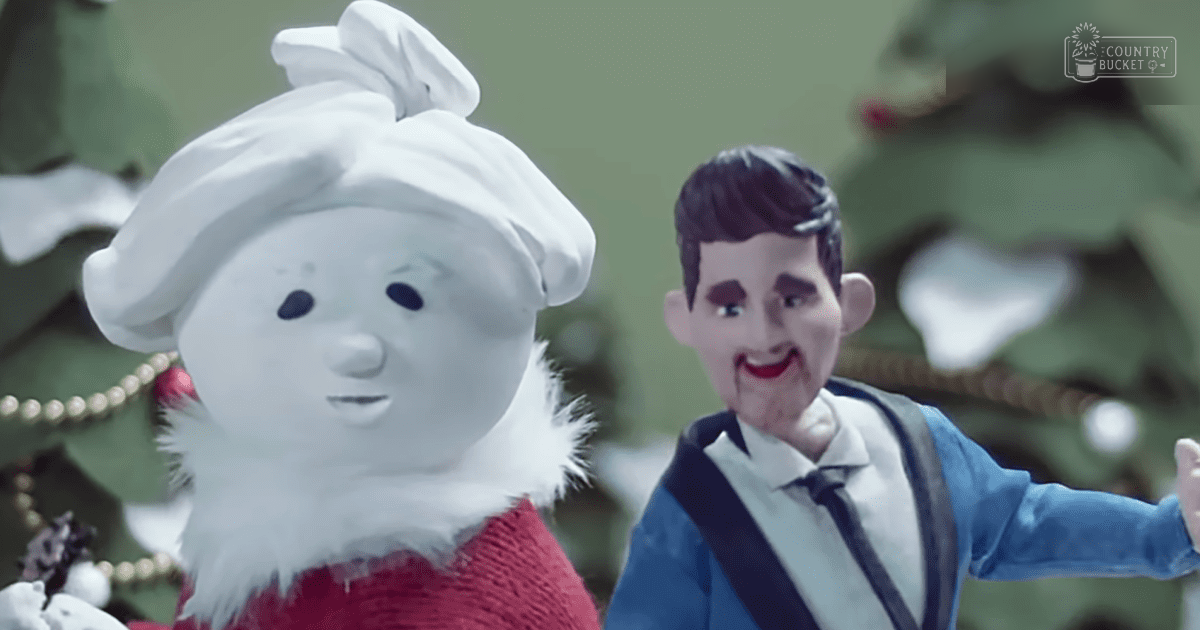A snowman character in a red knit sweater and white hat stands before a decorated Christmas tree indoors during the holiday season.