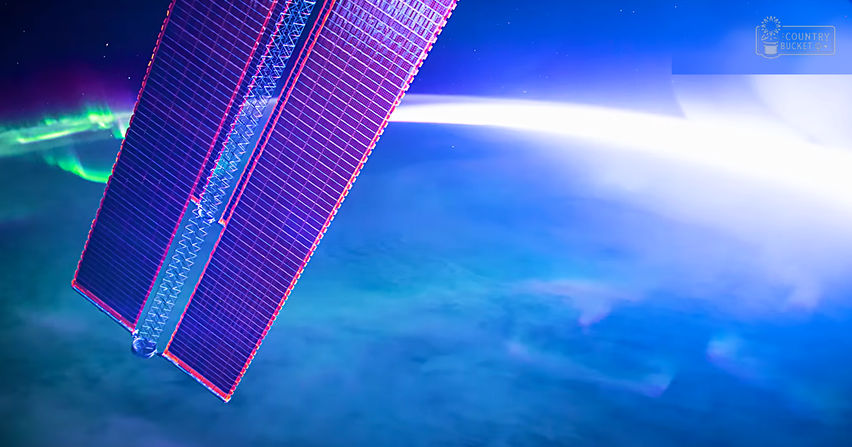 A satellite in outer space with solar panels, showing Earth below with auroras and stars in the background. The text 'Madly Odd' is visible.