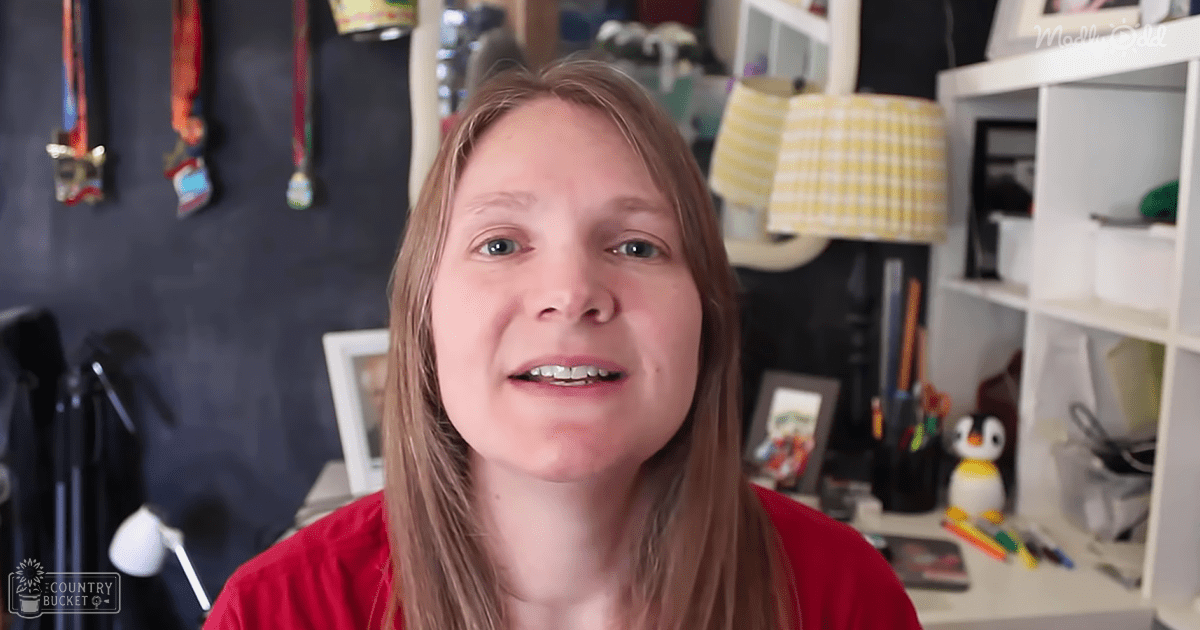 A young adult female wearing a bright red, relaxed fit crew neck long-sleeve shirt in a modern casual indoor setting with home office furniture and decor.