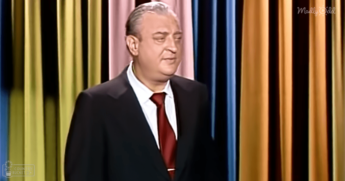 Middle-aged to older adult male in a formal setting, wearing a well-fitted dark suit jacket with a white shirt and red tie.