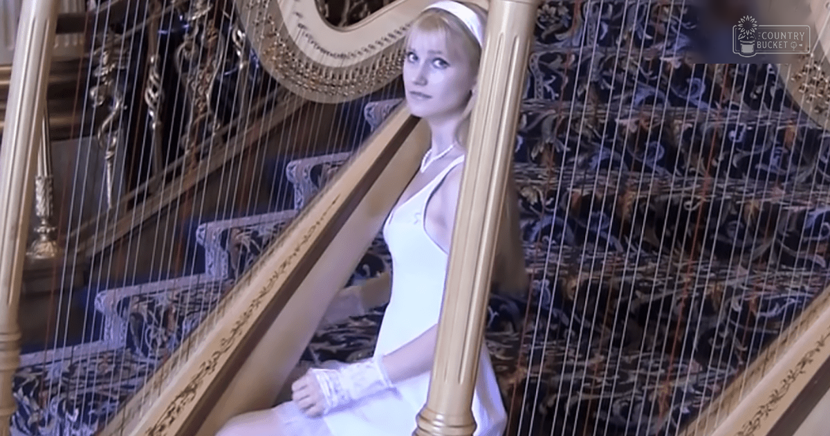 A young adult female dressed in a white sleeveless dress stands indoors, surrounded by ornate details of an opulent interior with intricate carvings and luxurious furniture.