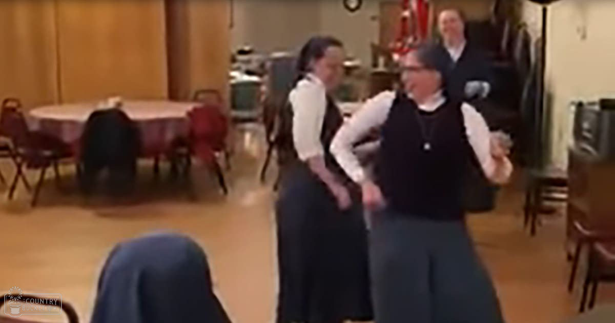 Two older adults dancing indoors at a community center with wooden floors and walls under natural light.