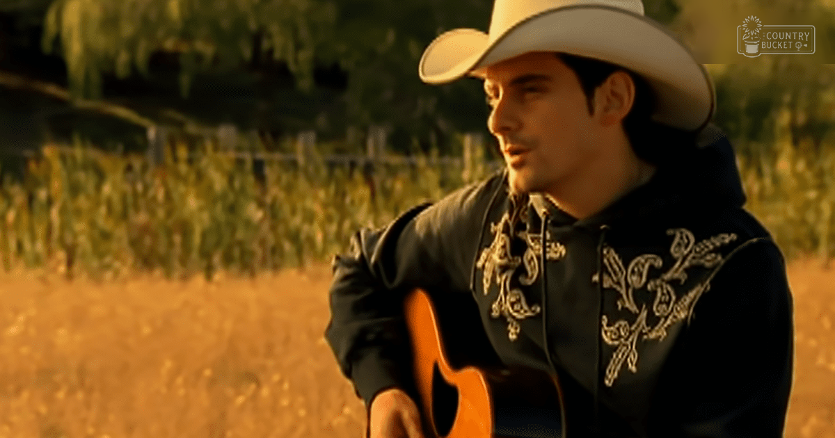 A young adult male in a rural setting with intricate gold-embroidered black leather jacket under warm evening light.