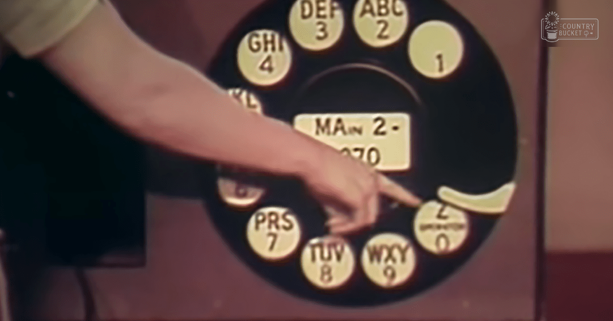 A hand wearing a white shirt sleeve dials a rotary phone with numbers '2-70' visible.