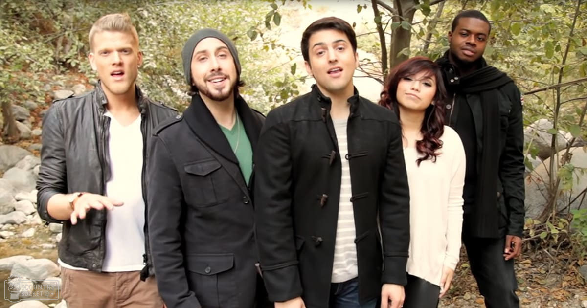 Five young adults in a forested park setting, wearing casual outdoor attire under soft natural light.