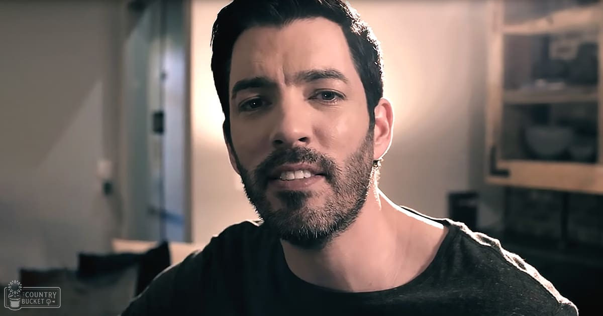 A young adult male in a relaxed fit crew neck t-shirt with short sleeves, wearing modern casual wear indoors with soft lighting and warm tones dominating the background.