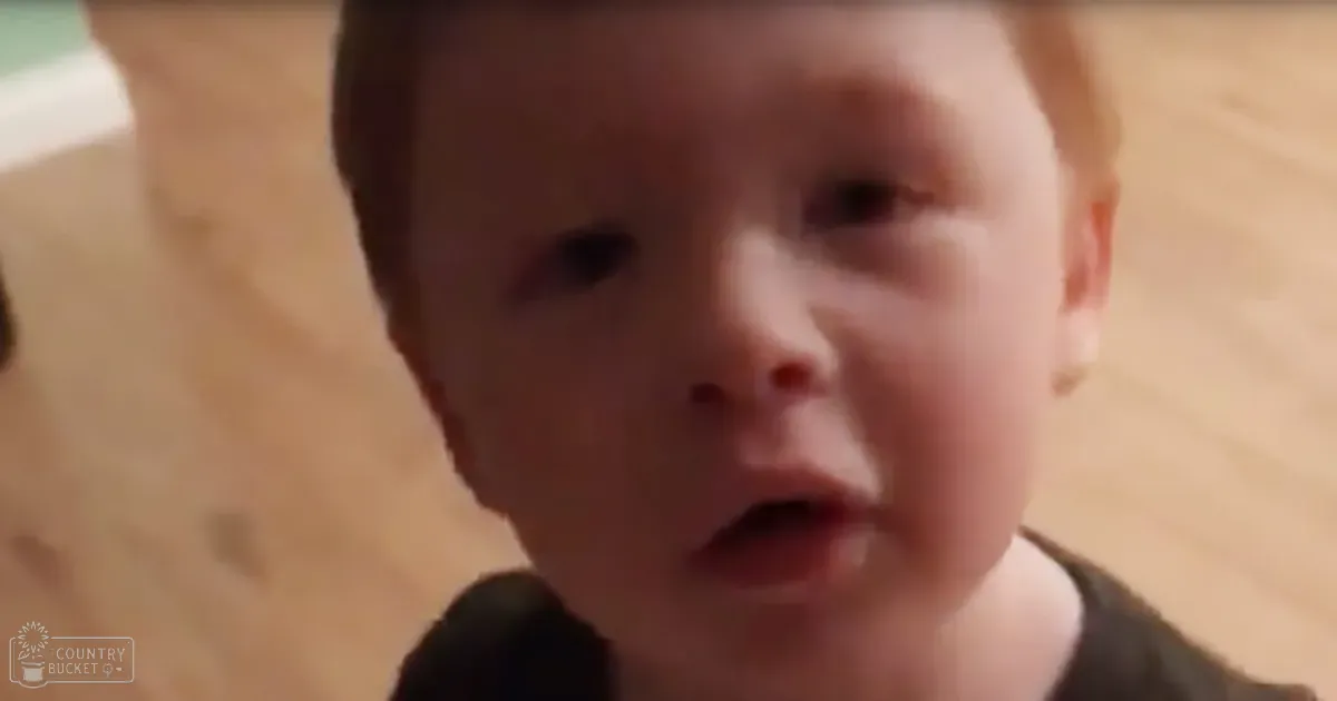 A toddler wearing a loose-fitting dark-colored garment indoors with wooden flooring