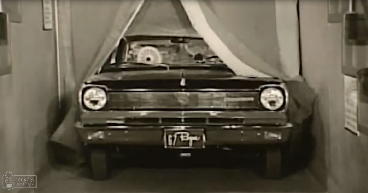 A vintage car with a license plate reading '67 B' displayed indoors, likely in a showroom or garage setting.