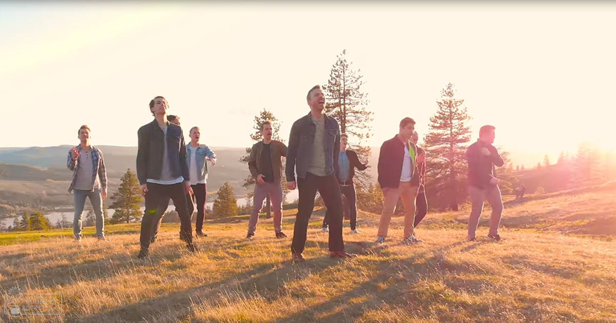 A group of young adult males standing in an open field at sunset or sunrise, wearing casual outdoor attire.