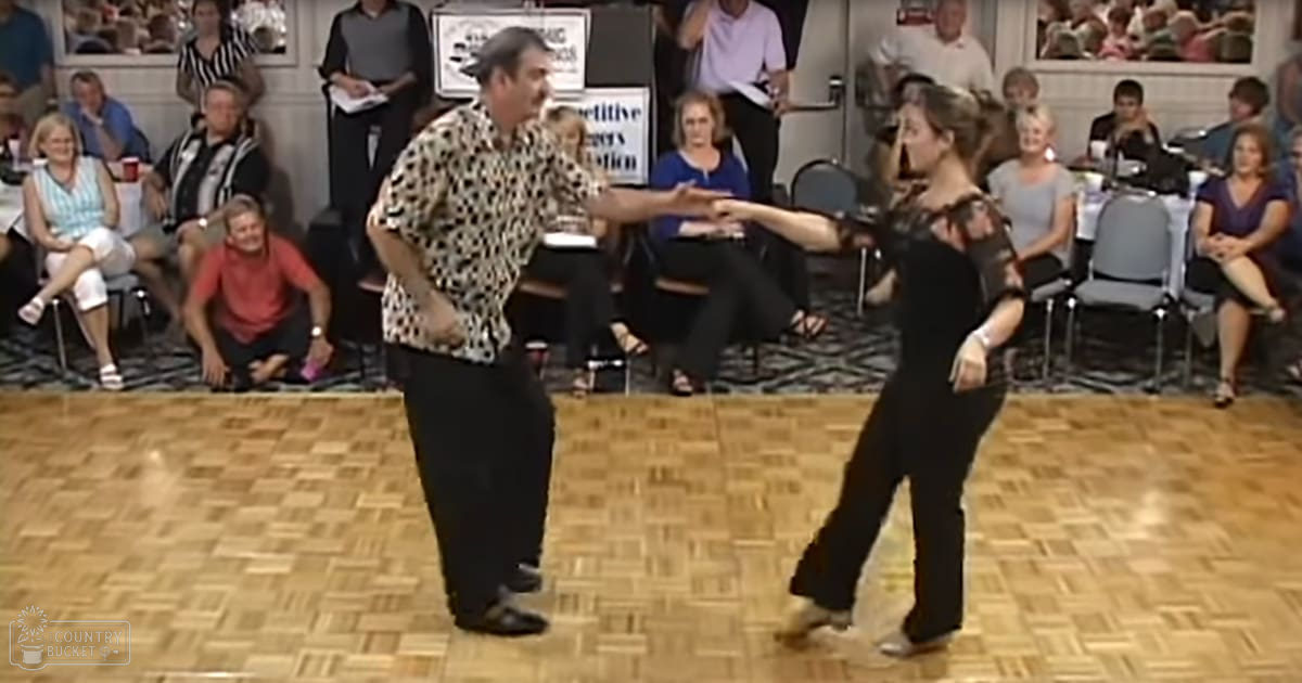 A couple dancing in a ballroom setting with an audience watching.