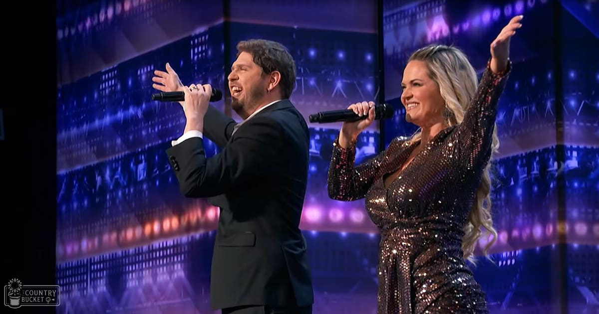 Musical performance scene with urban night backdrop, with a male in black suit jacket and female in sparkly dress holding microphones.
