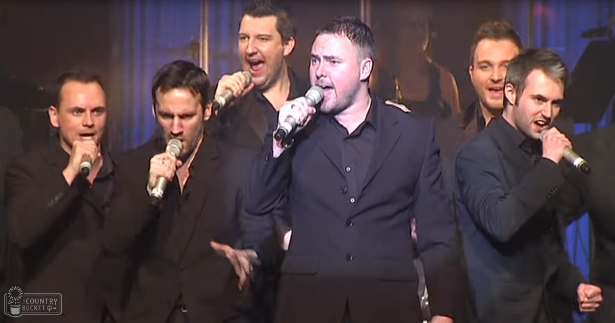 A group performing in what seems like a formal indoor performance setting with stage lighting.