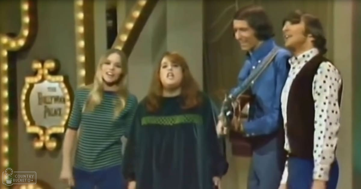 A musical performance scene from 'The Ed Sullivan Show' with children and adults dressed in late 1960s to early 1970s attire on a stage set for television performances.