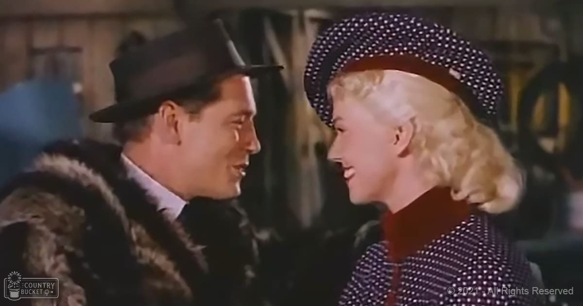 Two adults dressed in vintage-style attire, possibly from a film scene, set against an indoor backdrop with muted lighting and cluttered shelves.