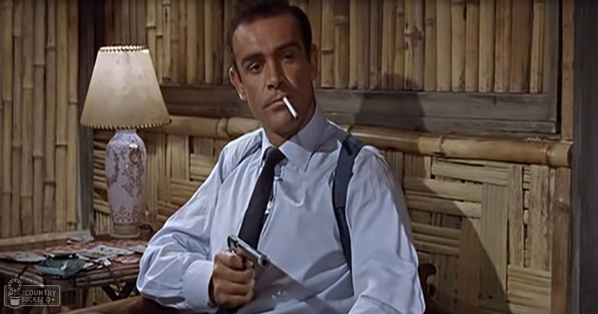 Adult male in a mid-20th century light blue dress shirt with dark tie, standing indoors with tropical-themed decor.
