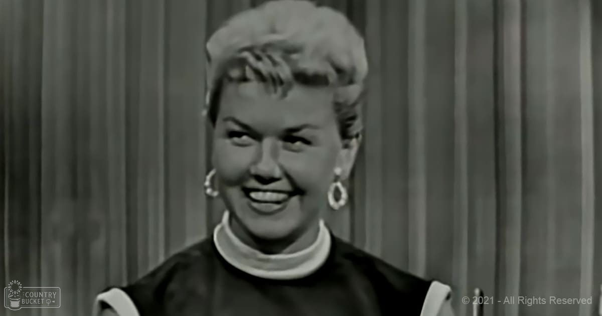 Adult female in an indoor setting wearing a dark fitted blouse with long puffed sleeves and large hoop earrings.