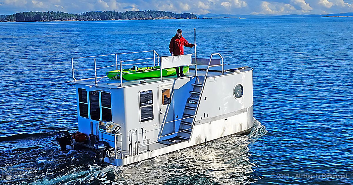 A coastal scene with a houseboat, calm waters, and distant land under partly cloudy skies.