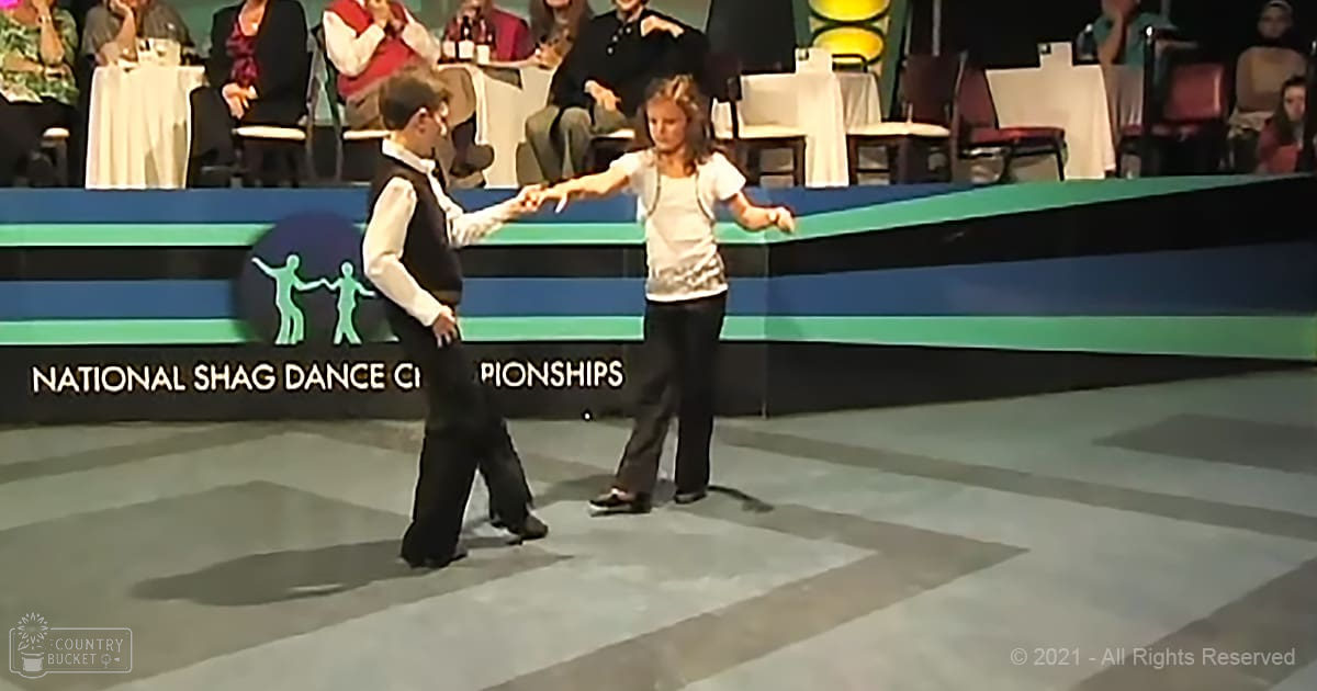 Young couple dancing at the National Shag Dance Championships on a stage with green and blue borders.
