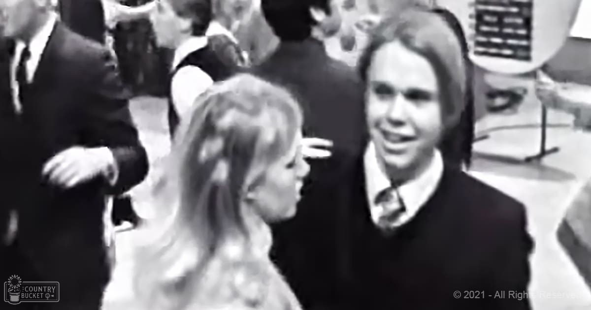 Young adult male and female at a formal indoor gathering with furniture and equipment suggesting an event or performance space.