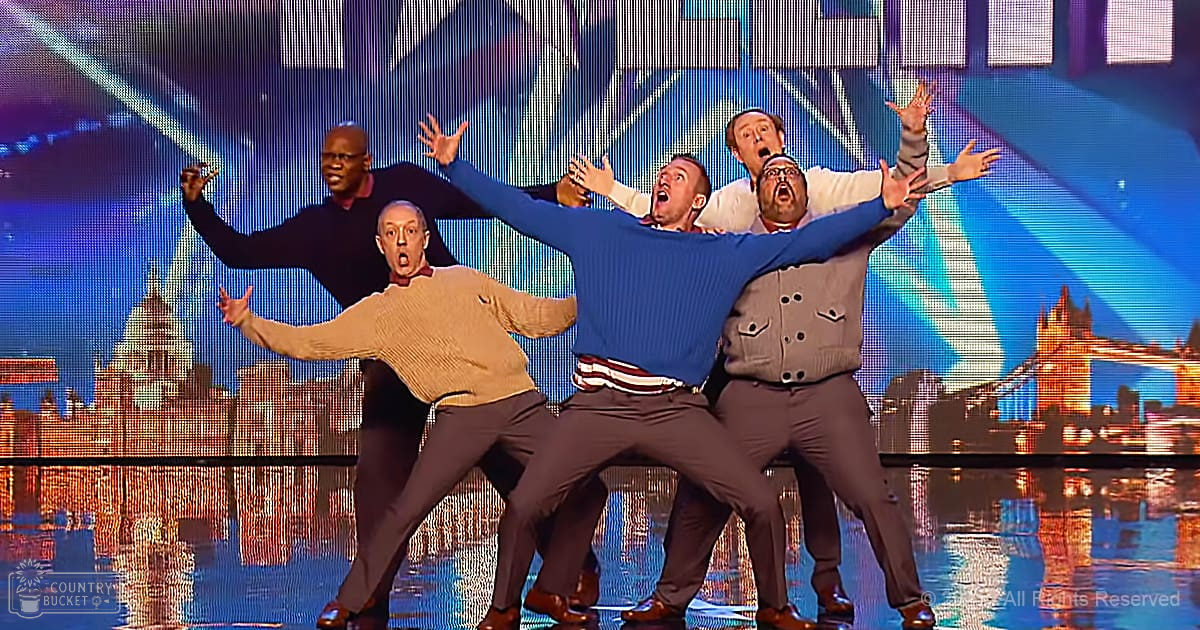 Group performing on stage with a cityscape backdrop at 'Britain's Got Talent' event.