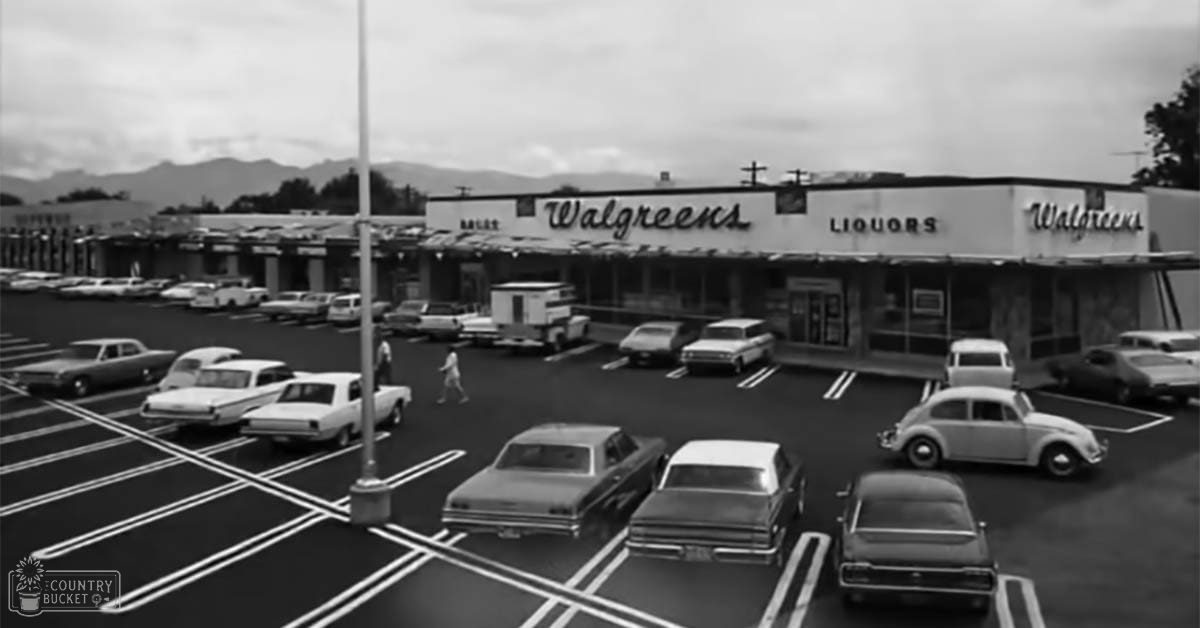 An urban area with a Walgreens store, parked cars, and mountains in the background; light suggests daytime but time of day or season unclear.