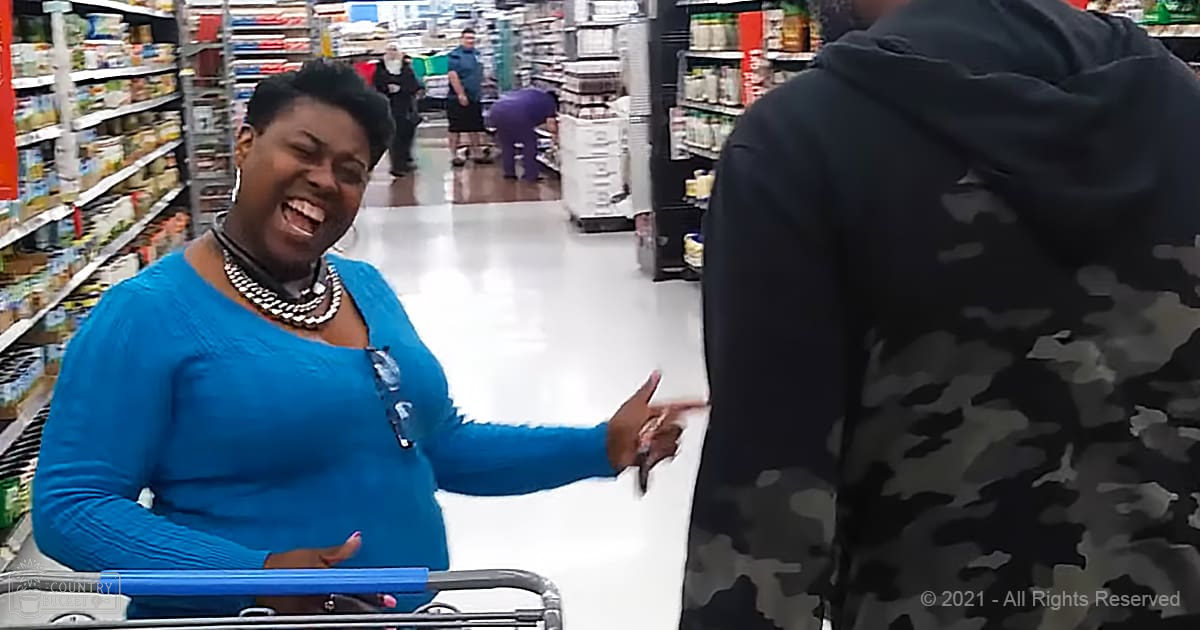 A middle-aged to older adult woman wearing a blue textured top and black and white beaded necklace shops in a well-lit grocery store with bright fluorescent lighting.