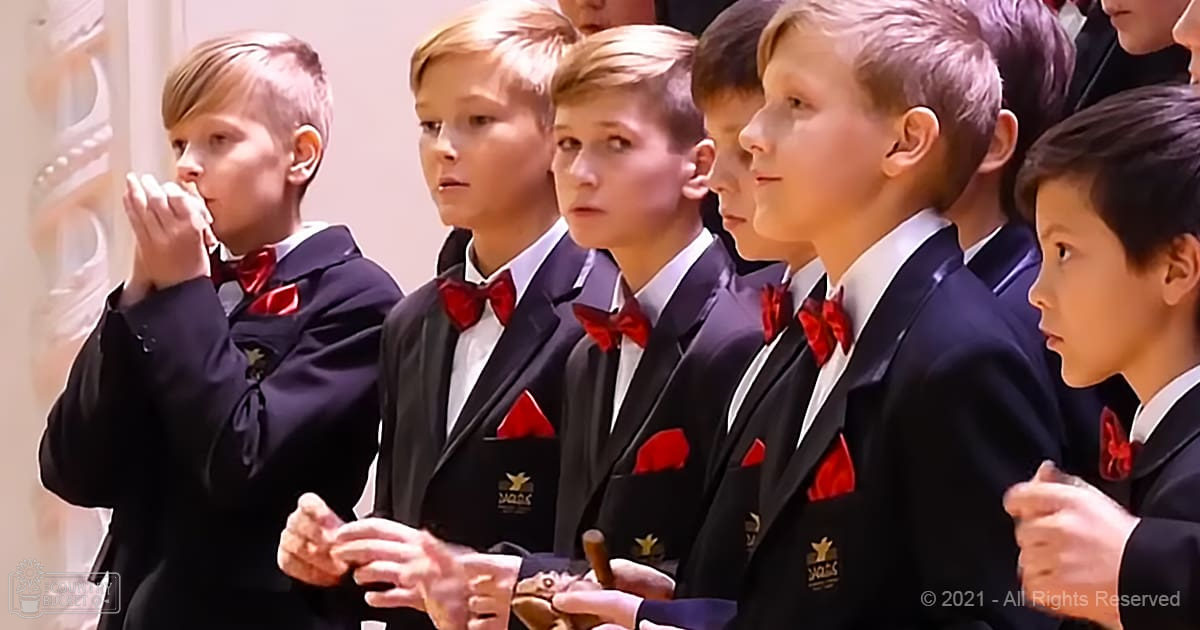 A group of young boys in formal attire stands indoors, likely at a school performance or ceremony.
