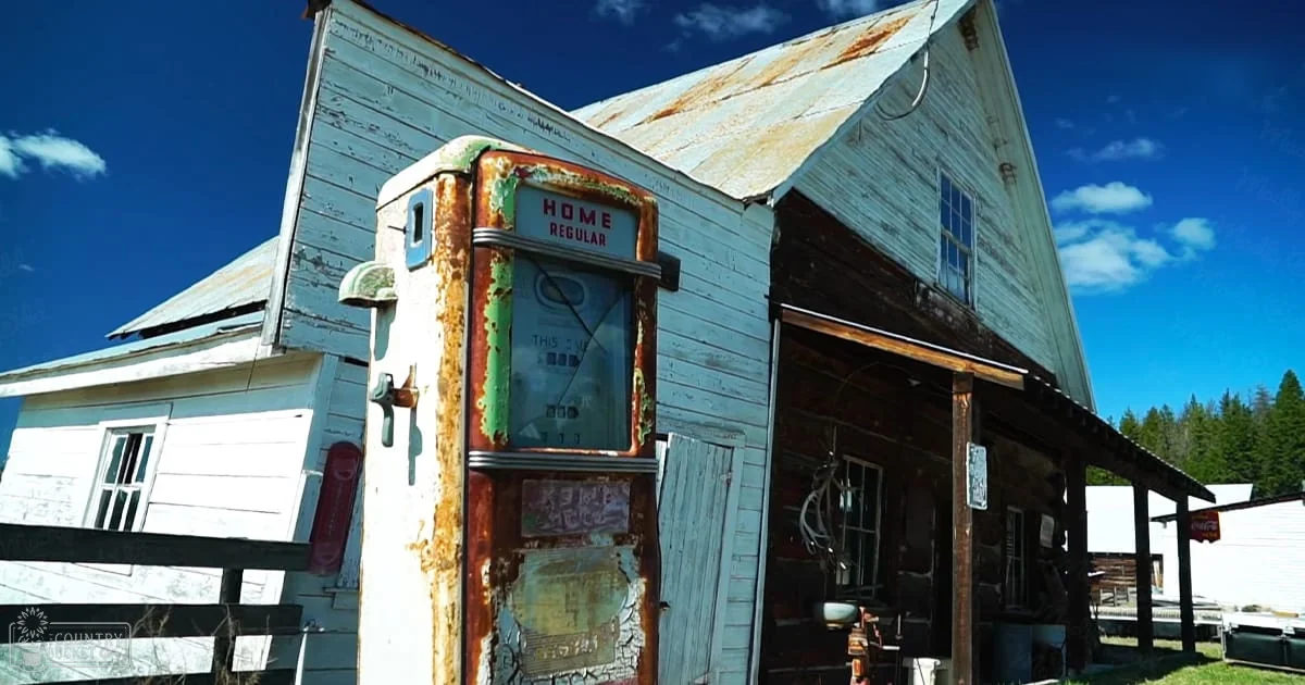 Rustic rural scene with a vintage gas pump, old wooden building, and Coca-Cola sign under clear midday sunlight.