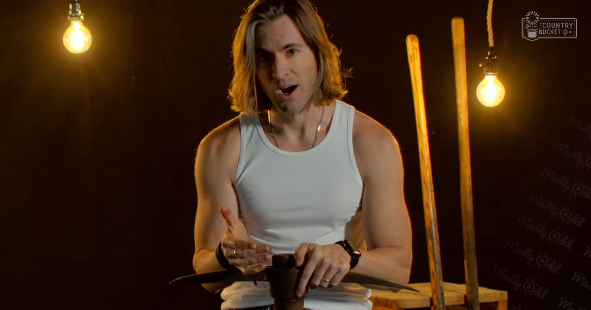Young adult male wearing a white tank top with a round neckline, modern casual wear, indoors with controlled lighting for a video production or performance.